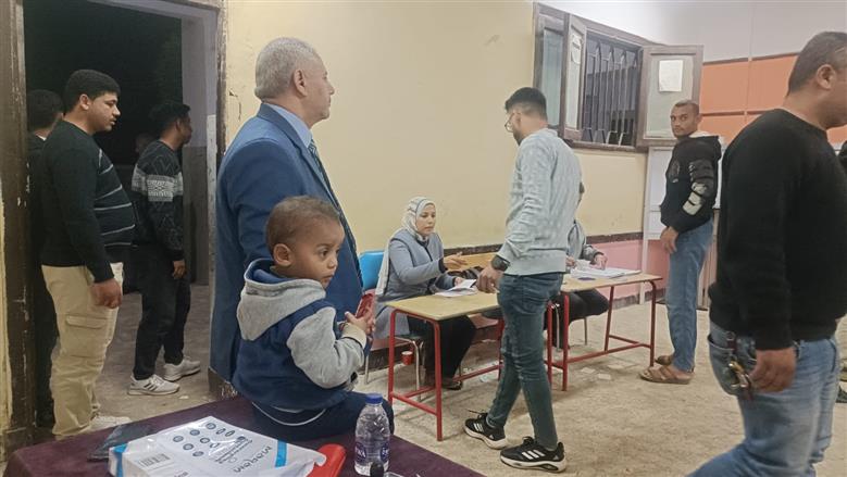 المستشار يحيى عزمي يحمل طفل الناخب لحين انتهاء والده من الإدلاء بصوته