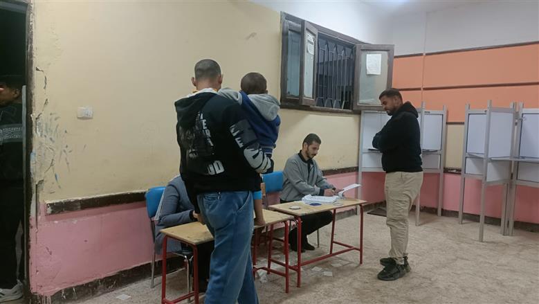 المستشار يحيى عزمي يحمل طفل الناخب لحين انتهاء والده من الإدلاء بصوته