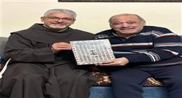 الأب بطرس دانيال يهدي ضياء الميرغني لوحة أسماء الله الحسني بعد الاطمئان على صحته